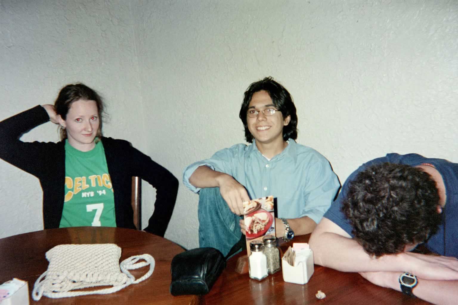 picture of a woman posing, a man with glasses smiling, and another man with his head down on a table