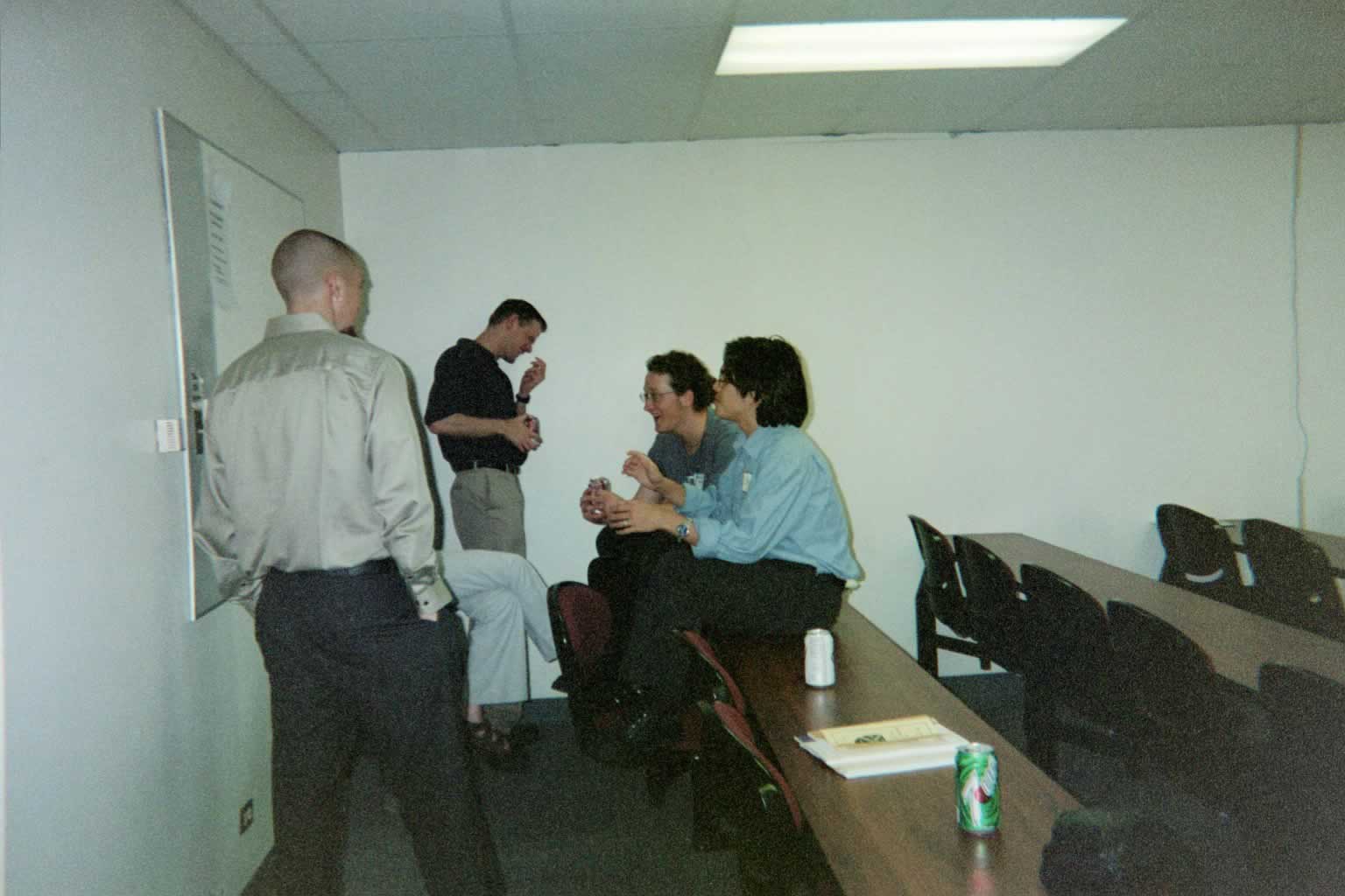 picture of students sitting on tables and chairs while talking and eating