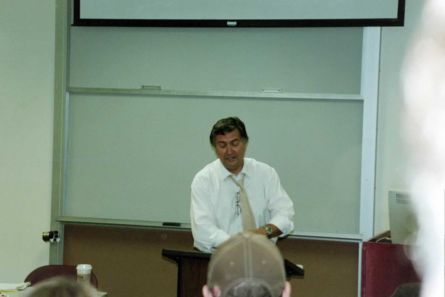 picture of Paul Marshall in a white dress shirt standing behind a podium speaking