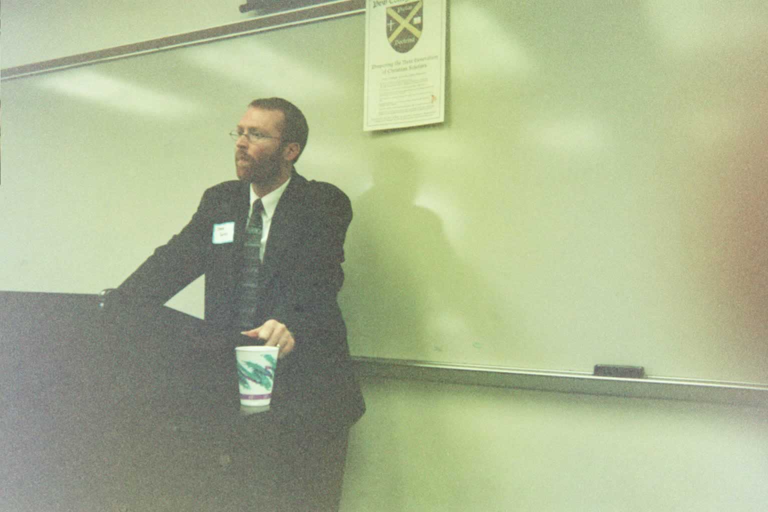 picture of a man in glasses standing behind a podium