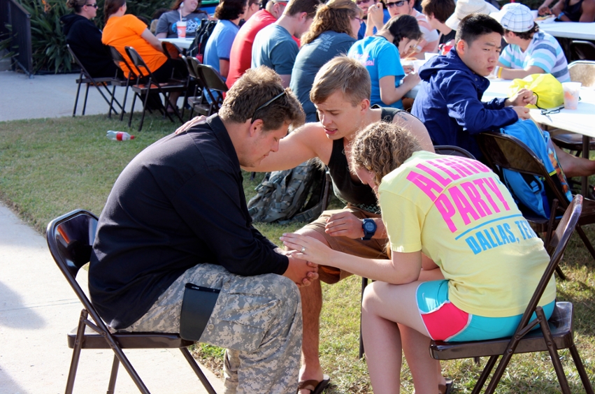 DBU students Chase Thomson (center) and Jessica Kowalski (right) pray with a student during Beach Reach 2013 in South Padre Island.