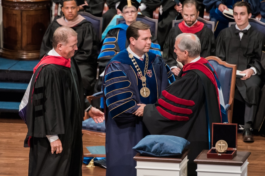 Dr.Wright is standing on stage shaking hands with a man. 