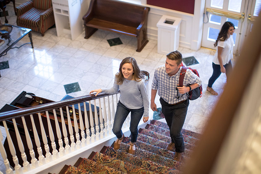 Students climb the stairs in the Spence dorm lobby