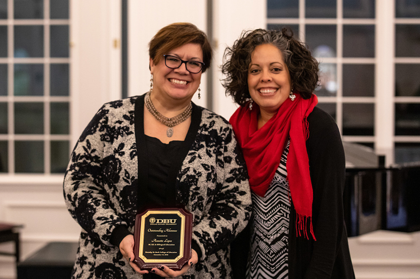 Two ladies standing together holding a plaque. 