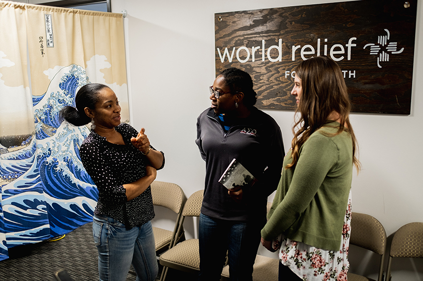 A DBU Student is standing with two women at World Relief in Fort Worth. 