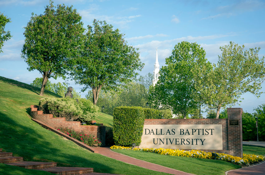 sunny morning - DBU campus - kiest gate DBU entry sign, trees, flowers, and chapel in the background