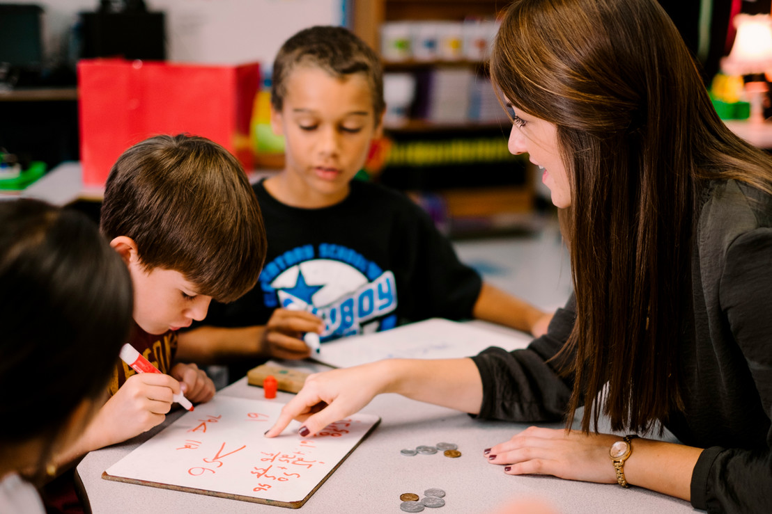 Female teacher teaching elementary children how to count money in Dallas, Texas