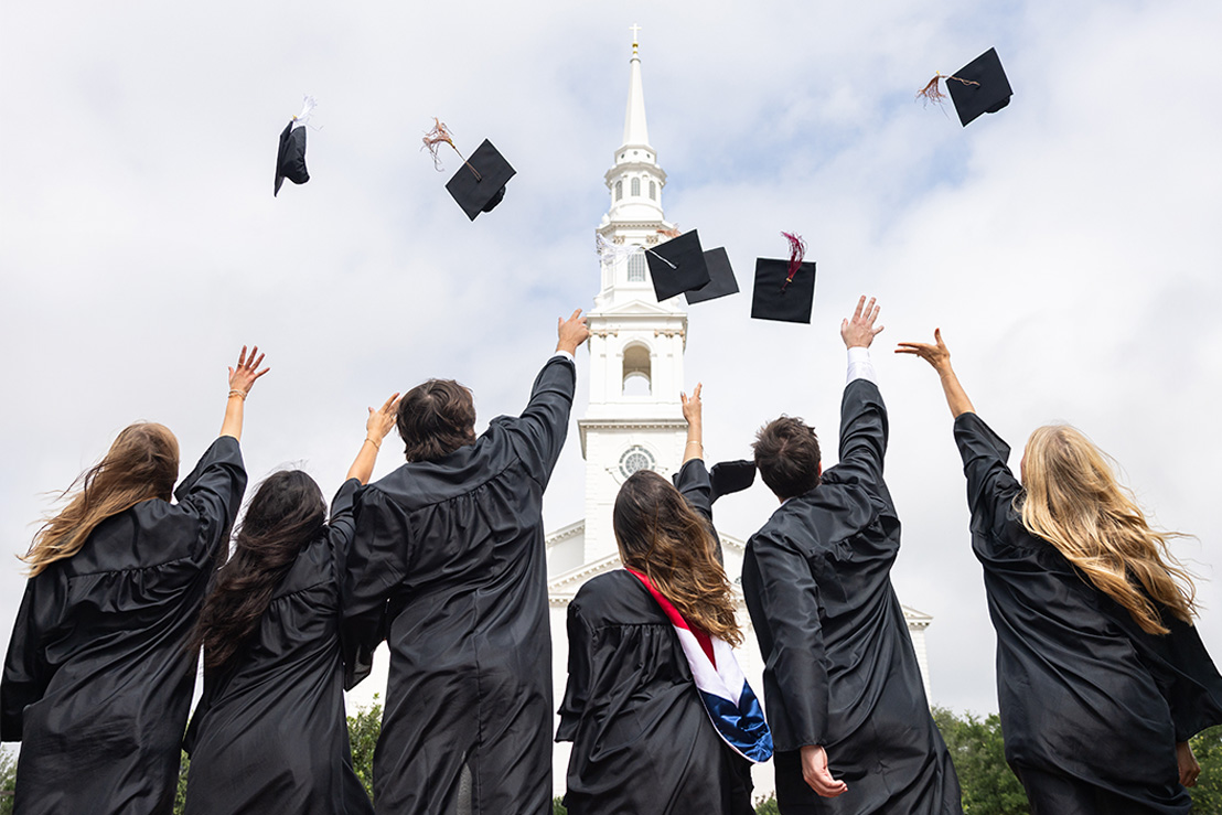 College students who graduated celebrating by tossing graduation caps up in the air in Dallas, Texas