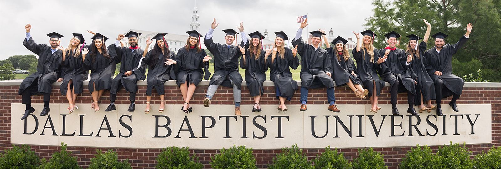 DBU graduate students sitting on DBU sign