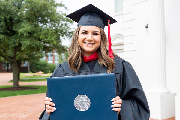 DBU graduate standing outside