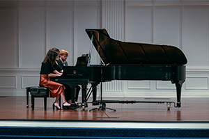 Two people playing piano on a stage