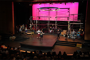 A stage with people performing and a large screen displaying visuals.