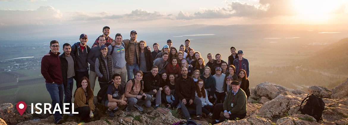 a group of DBU students smile in front of an Israeli valley