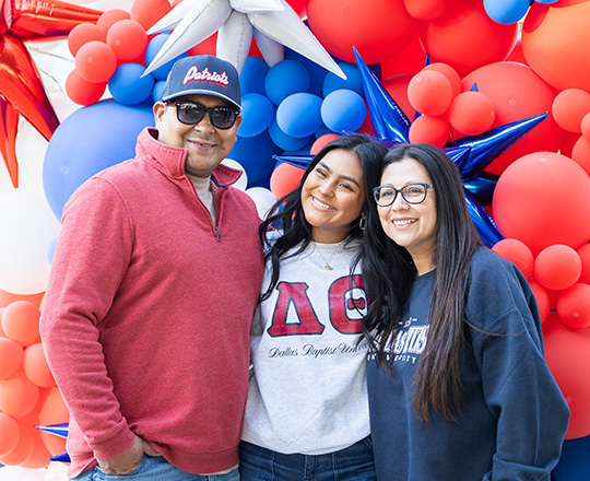 Family posing for a photo in front of balloons