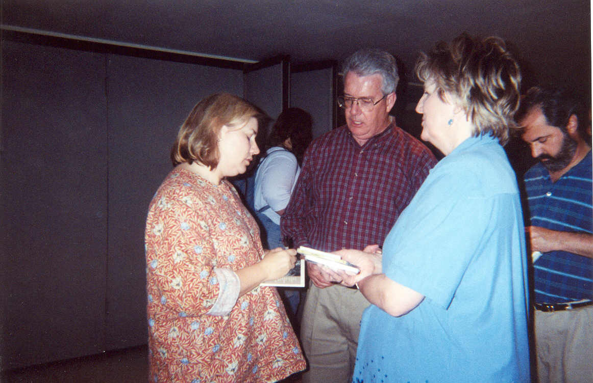 picture of 2 women speaking with a man while looking at a book