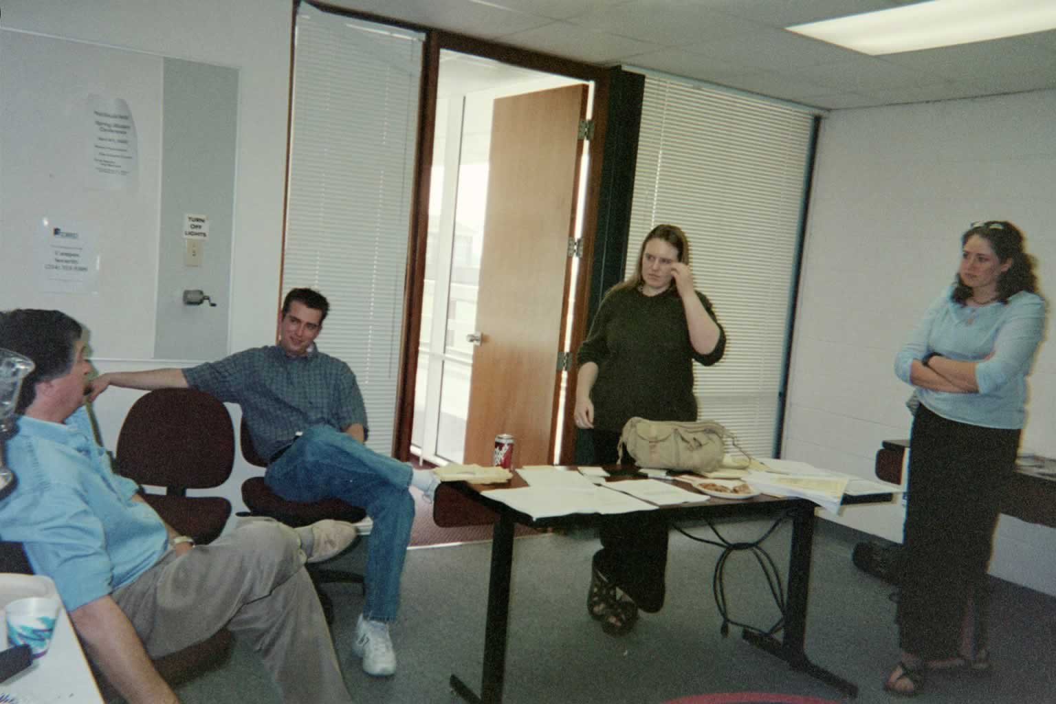 picture of Paul Marshall sitting and speaking while others are standing or sitting around him