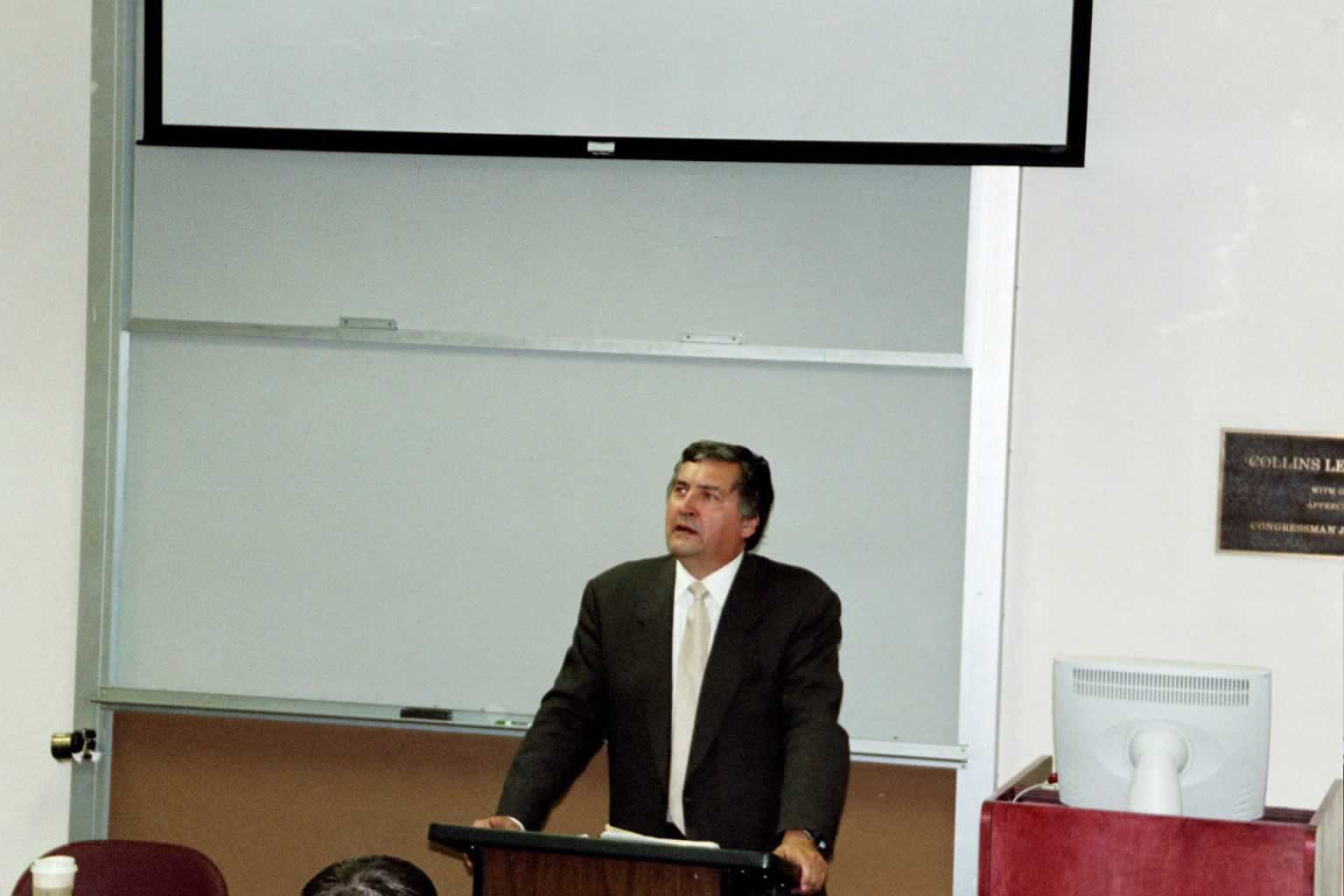 picture of Paul Marshall speaking behind a podium at the front of a class