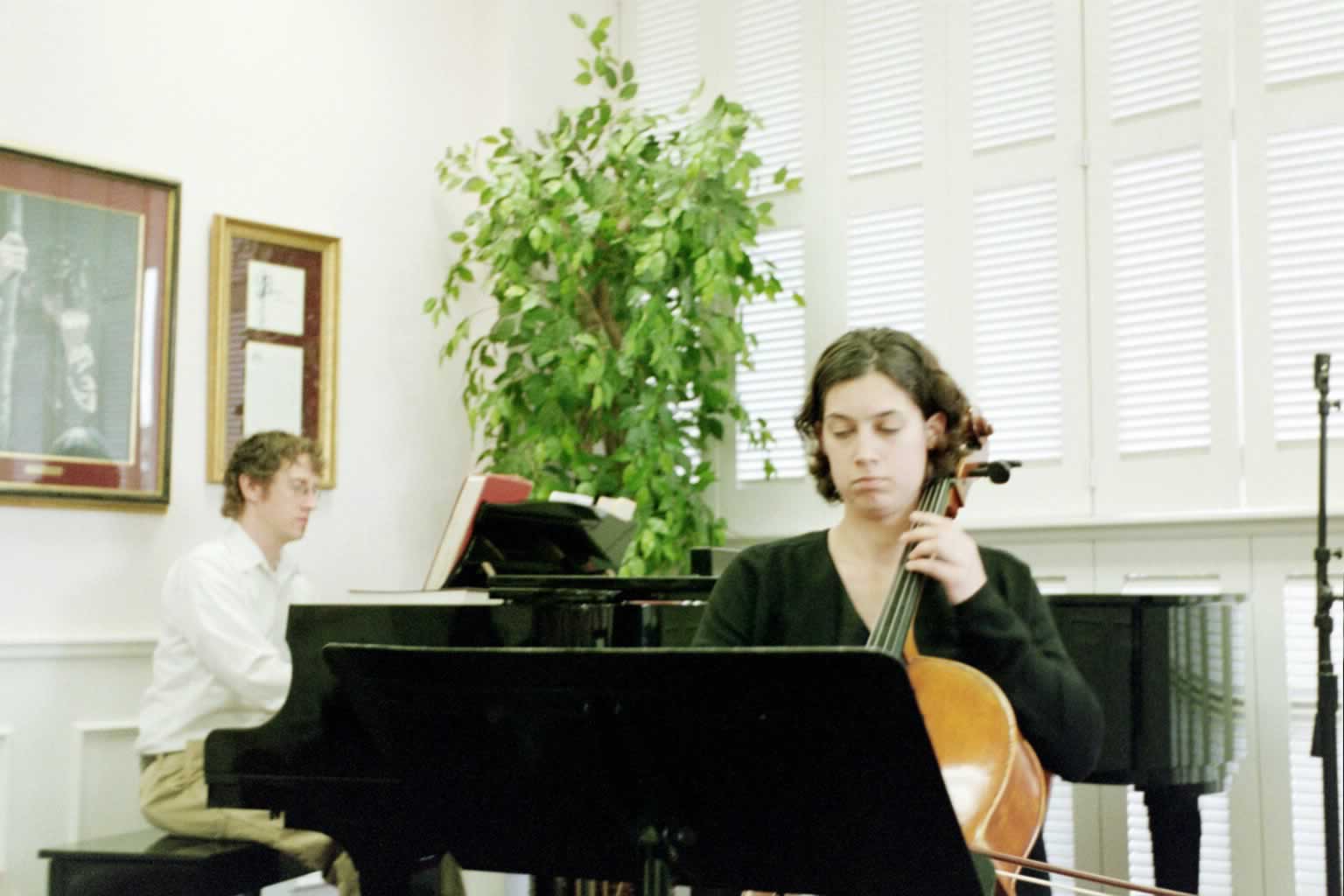 picture of a woman playing the cello with a man playing the piano behind her
