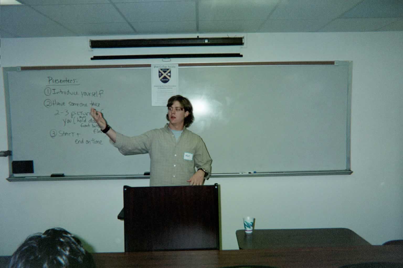picture of a student standing behind the podium with their arms raised