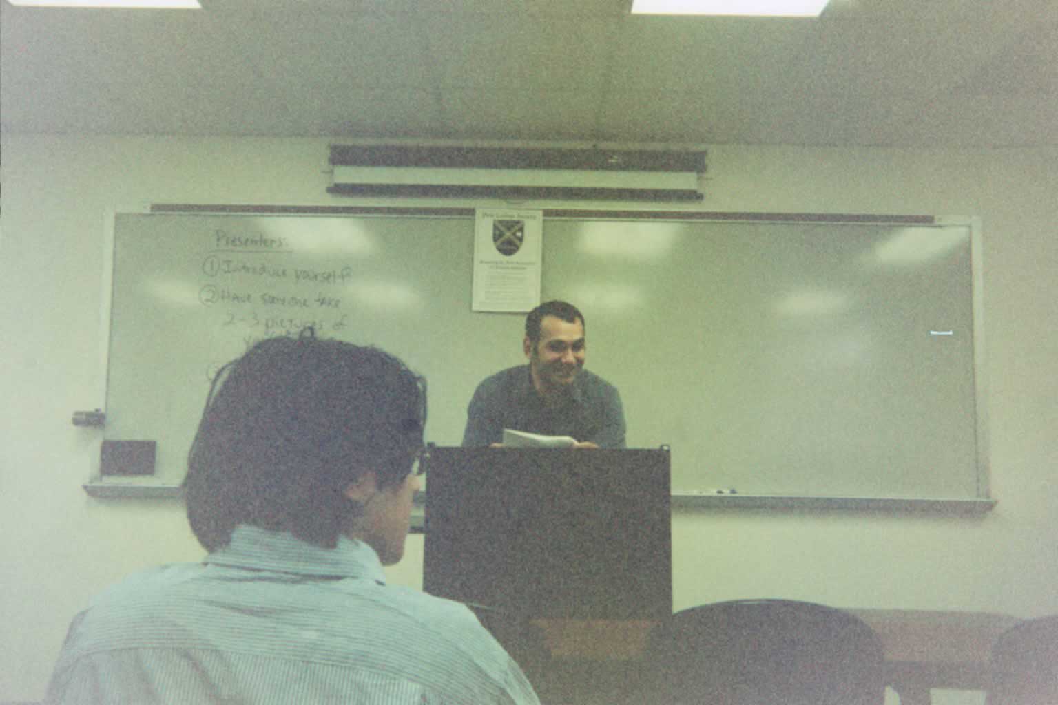 man standing behind a podium talking with the back of a man's head at the bottom of the picture