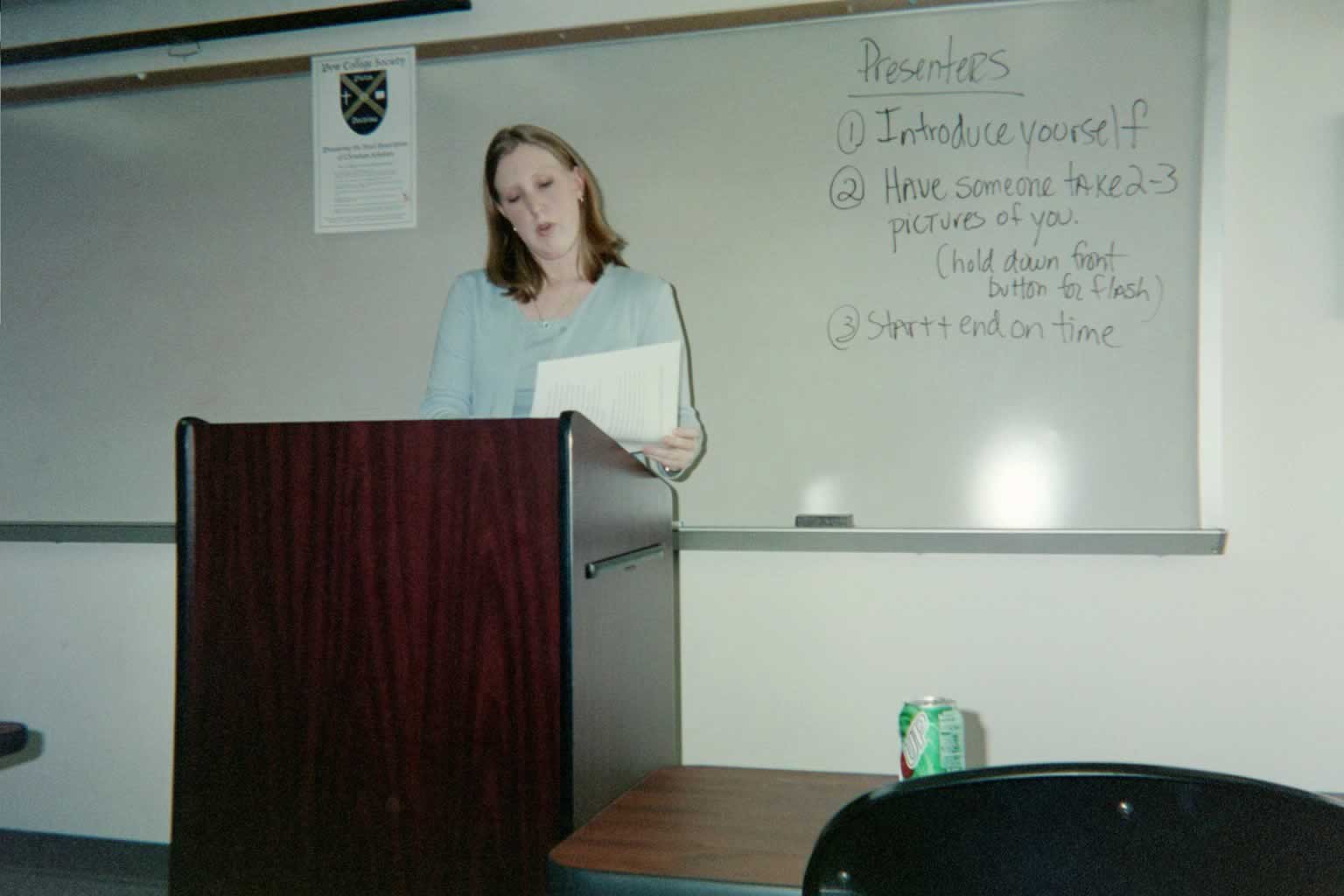 picture of a woman standing behind a podium looking at a piece of paper