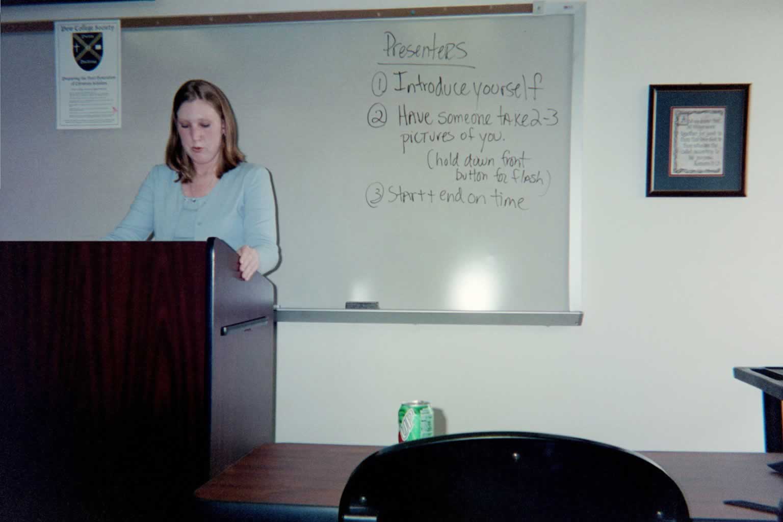 picture of a woman standing behind a podium looking down