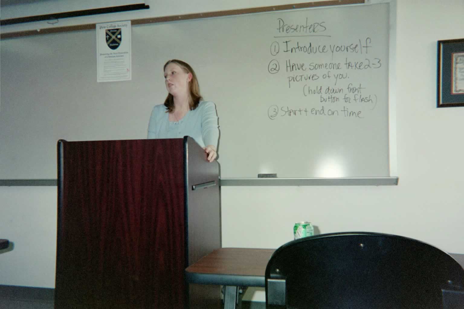 picture of a woman standing behind a podium tilting her head to the side