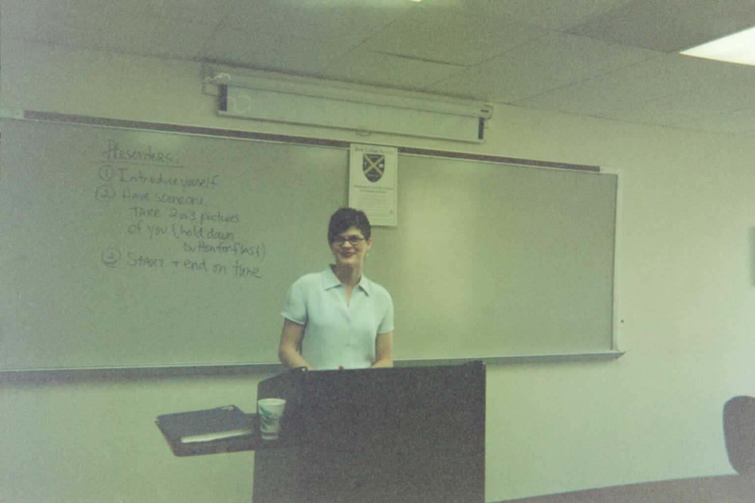 picture of a woman standing behind a podium smiling
