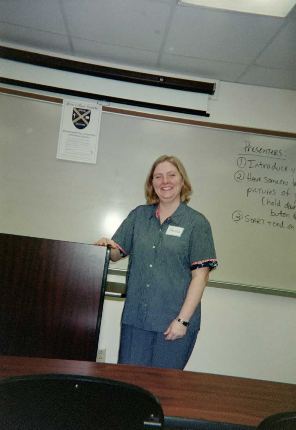 picture of a woman smiling next to a podium in a classroom