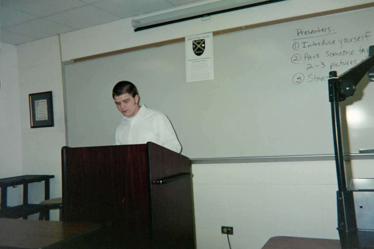 picture of a man in a white shirt standing behind a podium