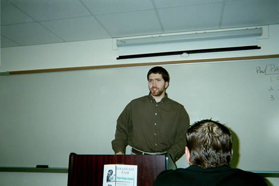 picture of a man in a green shirt standing behind a podium speaking