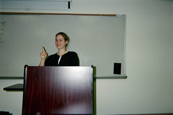 picture of a woman standing behind a podium smiling