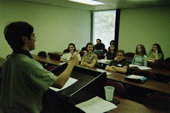  picture of students in a classroom listening to speaker behind the podium