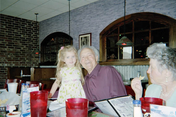 a little girl and man smiling while sitting in a restaurant table