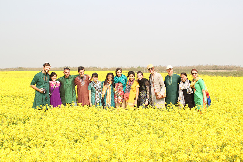 A group stands in a vibrant yellow field of flowers in Asia