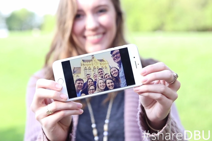 Sarah Edwards, a staff member, holds up a photo of her favorite memory from a travel study with DBU