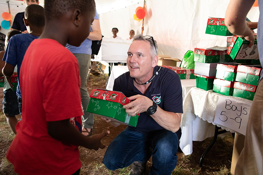 A DBU Faculty Member is handing a box to young boy. 