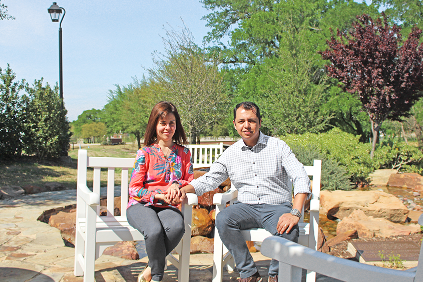 A man and his wife are sitting in chairs next to each other. They are holding hands and smiling. 