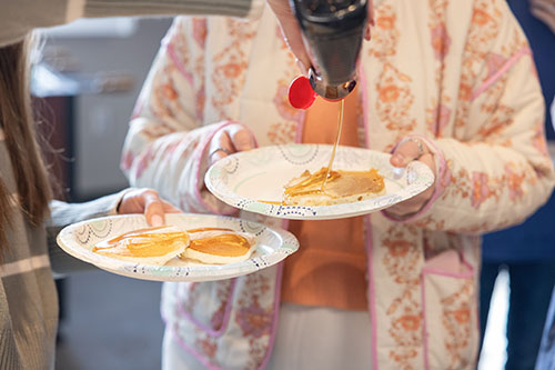 pancake syrup being poured on a pancake someone is holding