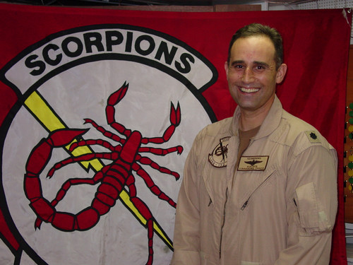 Bridget Reis's dad in front of red Scorpions squadron banner