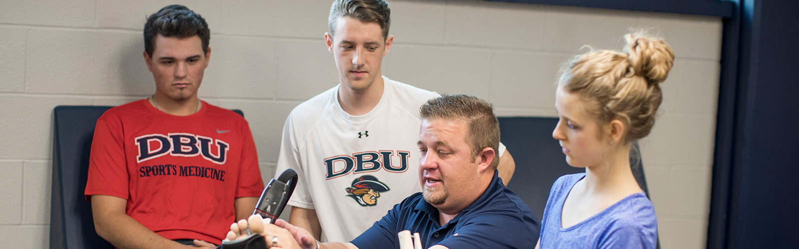 athletic trainer working with athlete while interns watch