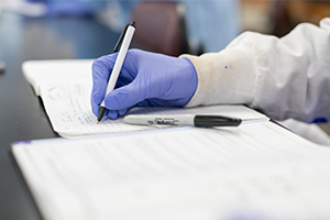 gloved hand holding pen working in a journal