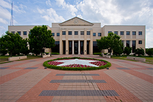 looking at a building from the outside - large star on ground with flowers around in a circle