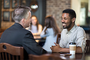 student and faculty chatting while enjoying coffee