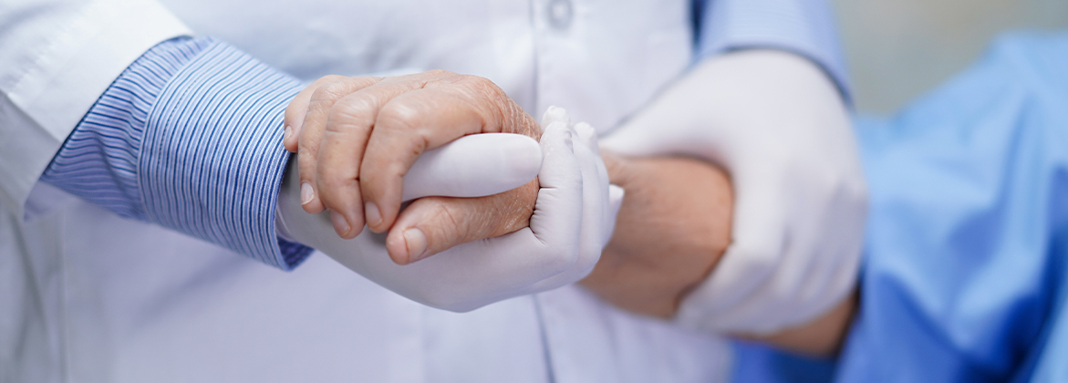 gloved hand holding hands with the patients hand