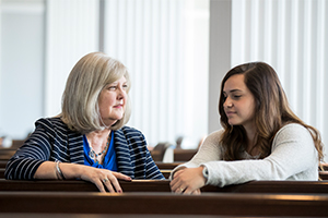 picture of professor with student sitting down in the chapel